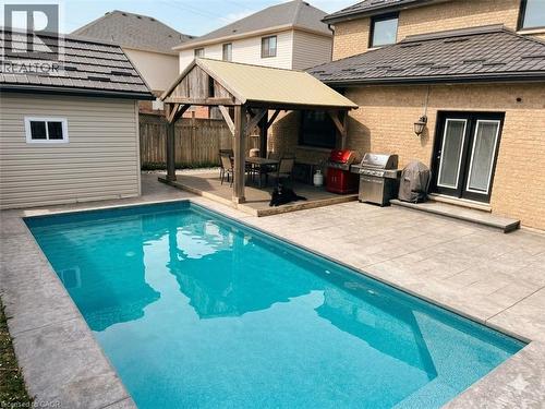 Backyard featuring an in-ground swimming pool, a covered patio with a wood-finish pergola, and textured paver stone decking - 6 Second Road W, Hamilton, ON - Outdoor With In Ground Pool With Exterior