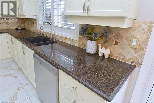 Kitchen featuring tasteful backsplash, dishwasher, white cabinetry, light marble finish floors, and dark stone countertops - 5109 Blue Spruce Avenue, Burlington, ON - Indoor Photo Showing Kitchen With Double Sink