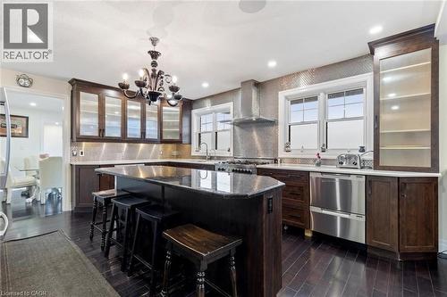 Kitchen featuring dark hardwood / wood-style flooring, a kitchen island, wall chimney exhaust hood, and stainless steel range oven - 1073 North Service Road, Hamilton, ON - Indoor