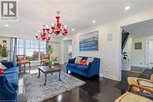 Living room with dark hardwood / wood-style flooring, ornamental molding, and an inviting chandelier - 1073 North Service Road, Hamilton, ON - Indoor Photo Showing Living Room