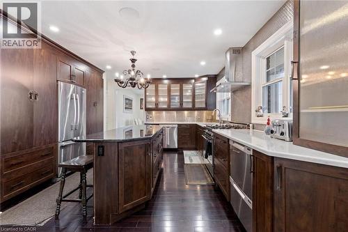 Kitchen with stainless steel appliances, wall chimney range hood, decorative light fixtures, an inviting chandelier, and a center island - 1073 North Service Road, Hamilton, ON - Indoor Photo Showing Kitchen With Upgraded Kitchen
