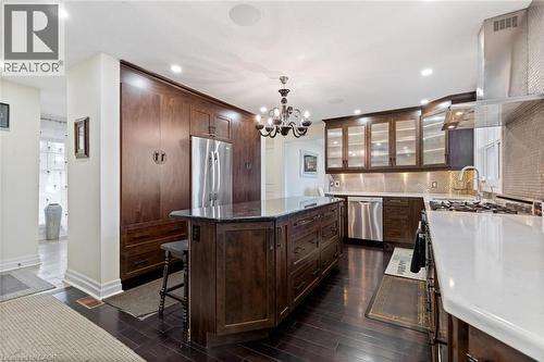 Kitchen featuring pendant lighting, dark wood-type flooring, range hood, appliances with stainless steel finishes, and a kitchen island - 1073 North Service Road, Hamilton, ON - Indoor Photo Showing Kitchen With Upgraded Kitchen