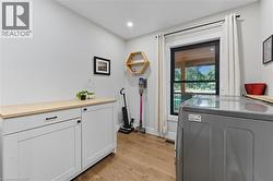 Washroom featuring washer / dryer, light wood-style floors, cabinet space, and recessed lighting - 