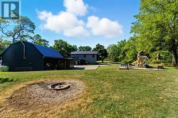 View of grassy yard featuring a playground, an outdoor structure, and view of scattered trees - 
