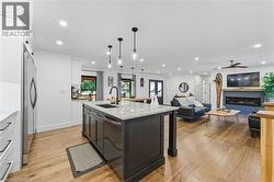 Kitchen featuring white cabinets, light stone countertops, light wood-style floors, decorative light fixtures, and open floor plan - 
