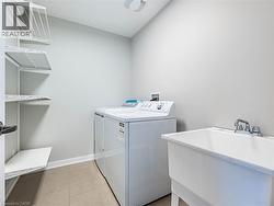 Laundry area with washing machine and clothes dryer and light tile patterned flooring - 