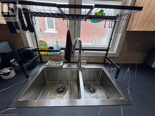 The kitchen features natural wood cabinetry, a double gooseneck sink framed by a wide window view, and access to the semi-refinished mudroom. Appliances included: fridge, stove, range hood, microwave, - 344 Paisley Road, Guelph, ON - 