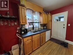 The kitchen features natural wood cabinetry, a double gooseneck sink framed by a wide window view, and access to the semi-refinished mudroom. Appliances included: fridge, stove, range hood, microwave, - 