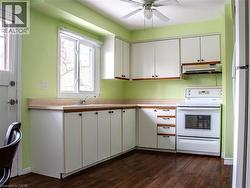 Dual tone kitchen with white appliances, light countertops, ceiling fan, dark wood-style floors, and dual tone cabinets - 