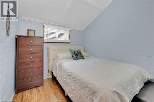 Room featuring light blue shiplap walls, wood-finish flooring, and a white slatted window blind - 17 Maple Lane, Rainham, ON - Indoor Photo Showing Bedroom