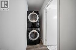 Laundry area with estacked washer and dryer and light wood finished floors - 