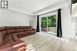 Living room with light wood finished floors, a tray ceiling, and recessed lighting - 