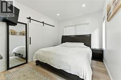 Bedroom with a barn door, recessed lighting, and light wood finished floors - 