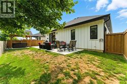 Back of house with a fenced backyard, a hot tub, a patio, board and batten siding, and a shingled roof - 