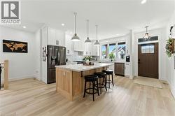 Kitchen with a center island, hanging light fixtures, stainless steel appliances, white cabinets, and recessed lighting - 