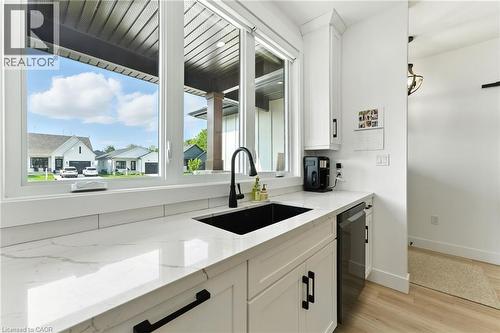 Kitchen featuring white cabinets, light stone countertops, light wood finished floors, and dishwasher - 9 Macneil Court, Port Burwell, ON - Indoor Photo Showing Kitchen