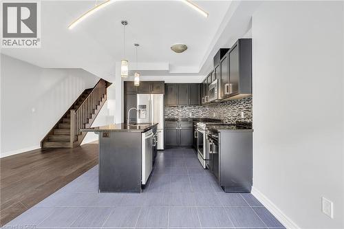 Kitchen with stainless steel appliances, decorative light fixtures, an island with sink, tasteful backsplash, and dark stone counters - 89 Sonoma Valley Crescent, Hamilton, ON - Indoor Photo Showing Kitchen With Stainless Steel Kitchen With Upgraded Kitchen