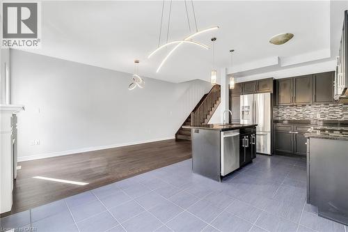 Kitchen with light tile patterned flooring, dark stone counters, pendant lighting, stainless steel appliances, and a center island with sink - 89 Sonoma Valley Crescent, Hamilton, ON - Indoor Photo Showing Kitchen With Upgraded Kitchen