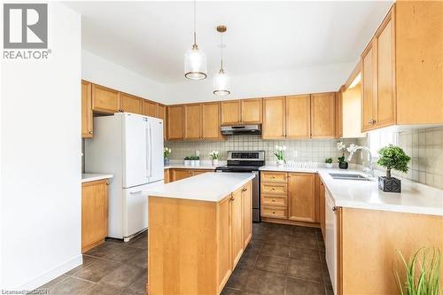 Kitchen featuring a kitchen island, white appliances, light countertops, light wood finish cabinets, and tasteful backsplash - 252 Thorner Drive Unit# Upper, Hamilton, ON - Indoor Photo Showing Kitchen With Double Sink