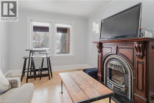 Living room with light wood-type flooring, a glass covered fireplace, and ornamental molding - 84 South Oval, Hamilton, ON - Indoor With Fireplace