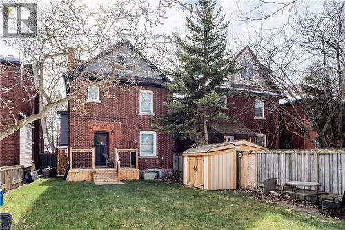 Back of house with a storage unit, a deck, brick siding, and a fenced backyard - 84 South Oval, Hamilton, ON - Outdoor