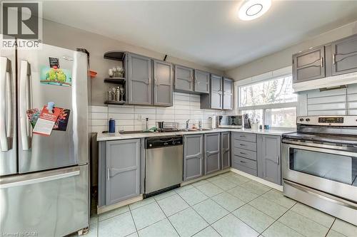 Kitchen with gray cabinetry, stainless steel appliances, light countertops, open shelves, and decorative backsplash - 142 Ewen Road, Hamilton, ON - Indoor Photo Showing Kitchen