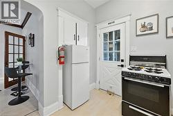 Kitchen featuring gas range oven, freestanding refrigerator, light wood finished floors, arched walkways, and white cabinetry - 
