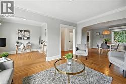 Living area with arched walkways, crown molding, wood finished floors, and radiator heating unit - 