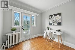 Home office with light wood finished floors, ornamental molding, and radiator - 