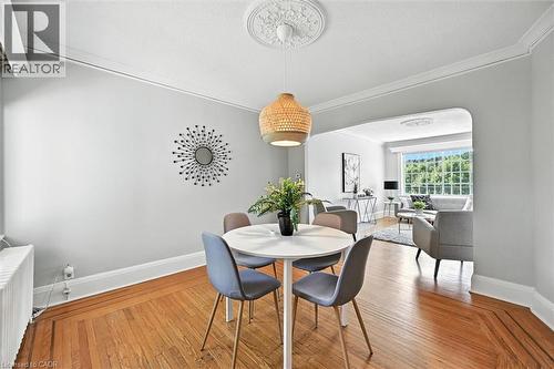 Dining space featuring arched walkways, radiator heating unit, crown molding, and light wood-style flooring - 1047 Main Street E, Hamilton, ON - Indoor Photo Showing Dining Room