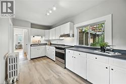 Kitchen with electric range, white cabinets, and dark countertops - 