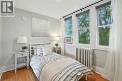 Bedroom with radiator, light wood finished floors, and cooling unit - 