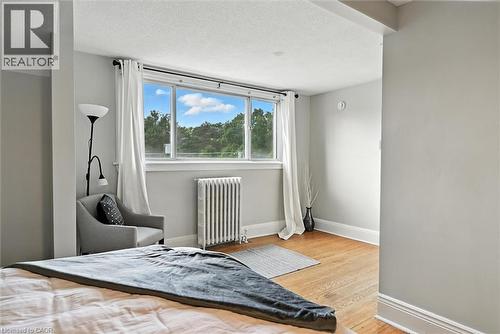 Bedroom featuring radiator heating unit, a textured ceiling, and light wood-style floors - 1047 Main Street E, Hamilton, ON - Indoor Photo Showing Bedroom