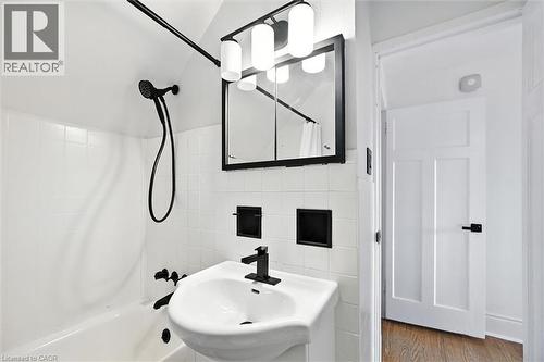 Bathroom featuring tile walls, shower / bath combo with shower curtain, and wood finished floors - 1047 Main Street E, Hamilton, ON - Indoor Photo Showing Bathroom