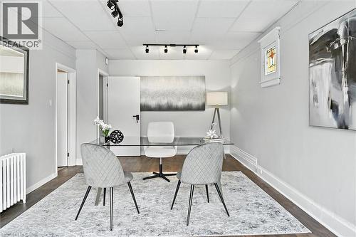 Home office featuring rail lighting, radiator heating unit, and dark wood-type flooring - 1047 Main Street E, Hamilton, ON - Indoor