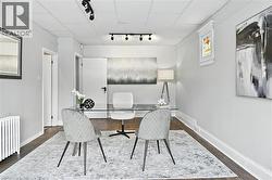 Home office featuring rail lighting, radiator heating unit, and dark wood-type flooring - 