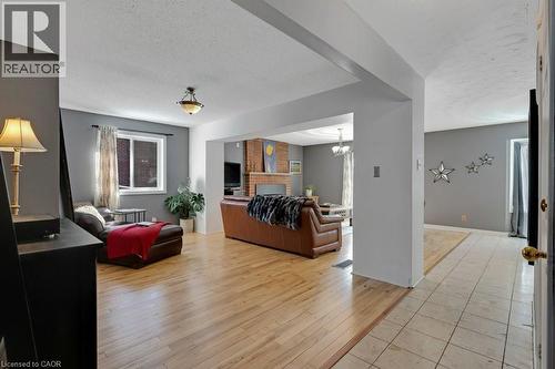 Living area featuring light wood-style flooring, a textured ceiling, a fireplace, and a chandelier - 148 Cowan Boulevard, Cambridge, ON - Indoor