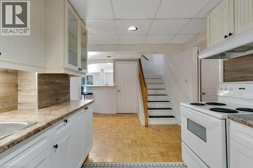 Lower Kitchen with white range with electric cooktop, glass fronted cabinets, a paneled ceiling, white cabinetry, and light countertops - 148 Cowan Boulevard, Cambridge, ON - Indoor Photo Showing Kitchen