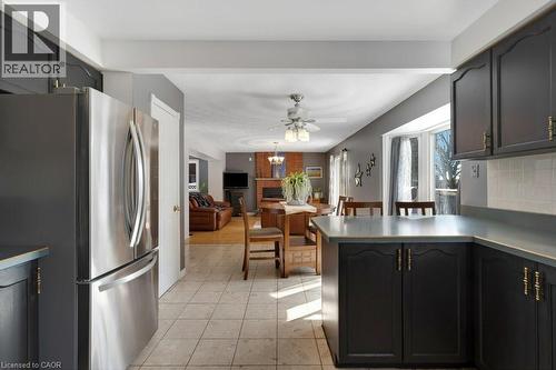 Kitchen featuring freestanding refrigerator, dark cabinetry, ceiling fan, a peninsula, and light tile patterned flooring - 148 Cowan Boulevard, Cambridge, ON - Indoor Photo Showing Kitchen