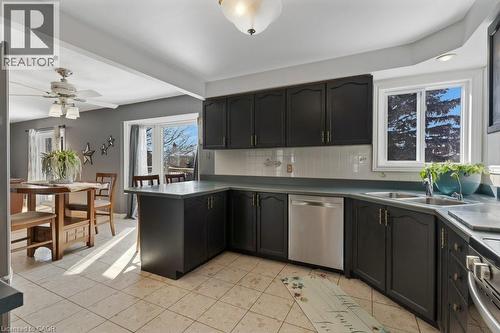 Kitchen featuring ceiling fan, stainless steel appliances, backsplash, dark countertops, and light tile patterned flooring - 148 Cowan Boulevard, Cambridge, ON - Indoor Photo Showing Kitchen With Double Sink