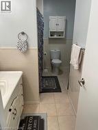 Bathroom with tile walls, tile patterned flooring, toilet, a wainscoted wall, and vanity - 