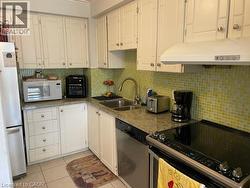 Kitchen featuring appliances with stainless steel finishes, a sink, white cabinets, and light tile patterned floors - 