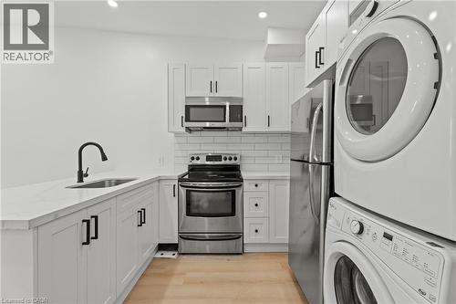 Kitchen with stainless steel appliances, white cabinetry, a peninsula, tasteful backsplash, and light wood finished floors - 93 John Street S, Hamilton, ON 