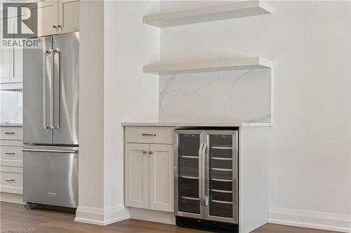 Bar featuring high end refrigerator, wine cooler, white cabinetry, light wood-style floors, and light stone counters - 16 Bosna Court, Hamilton, ON - Indoor