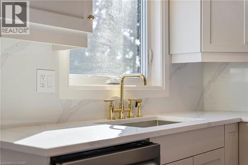 Kitchen view of white cabinets, light stone counters, stainless steel dishwasher, and backsplash - 16 Bosna Court, Hamilton, ON - Indoor Photo Showing Kitchen