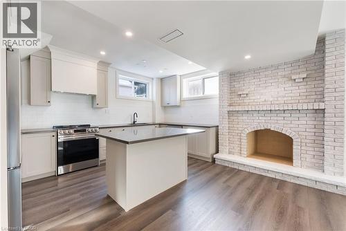 Kitchen featuring stainless steel appliances, a kitchen island, dark wood-style floors, dark countertops, and tasteful backsplash - 16 Bosna Court, Hamilton, ON - Indoor Photo Showing Kitchen With Upgraded Kitchen