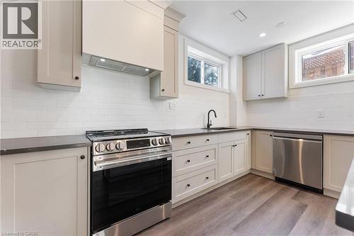 Kitchen with stainless steel appliances, light wood-type flooring, decorative backsplash, recessed lighting, and dark stone countertops - 16 Bosna Court, Hamilton, ON - Indoor Photo Showing Kitchen With Upgraded Kitchen