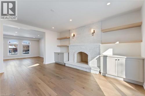 Unfurnished living room featuring a brick fireplace, light wood-style flooring, and recessed lighting - 16 Bosna Court, Hamilton, ON - Indoor With Fireplace