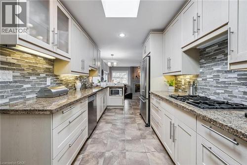 Granite countertops, glass backsplash, JennAire cooktop with bbq attachment. JennAire fridge. Glass fronted cabinetry. Breakfast bar. Skylight. - 3012 First Street, Burlington, ON - Indoor Photo Showing Kitchen With Upgraded Kitchen