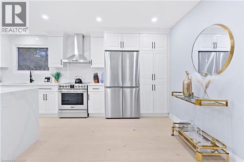 Kitchen with appliances with stainless steel finishes, wall chimney range hood, white cabinetry, recessed lighting, and tasteful backsplash - 19 Broad Street, Brantford, ON - Indoor Photo Showing Kitchen With Stainless Steel Kitchen With Upgraded Kitchen